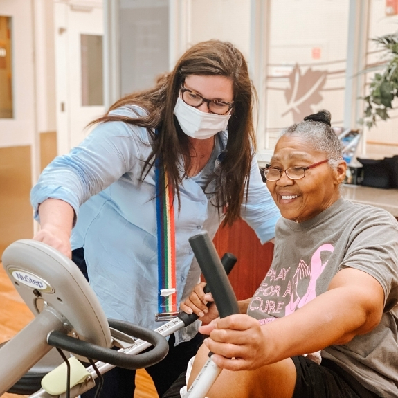 staff member works with woman on a stationary bike